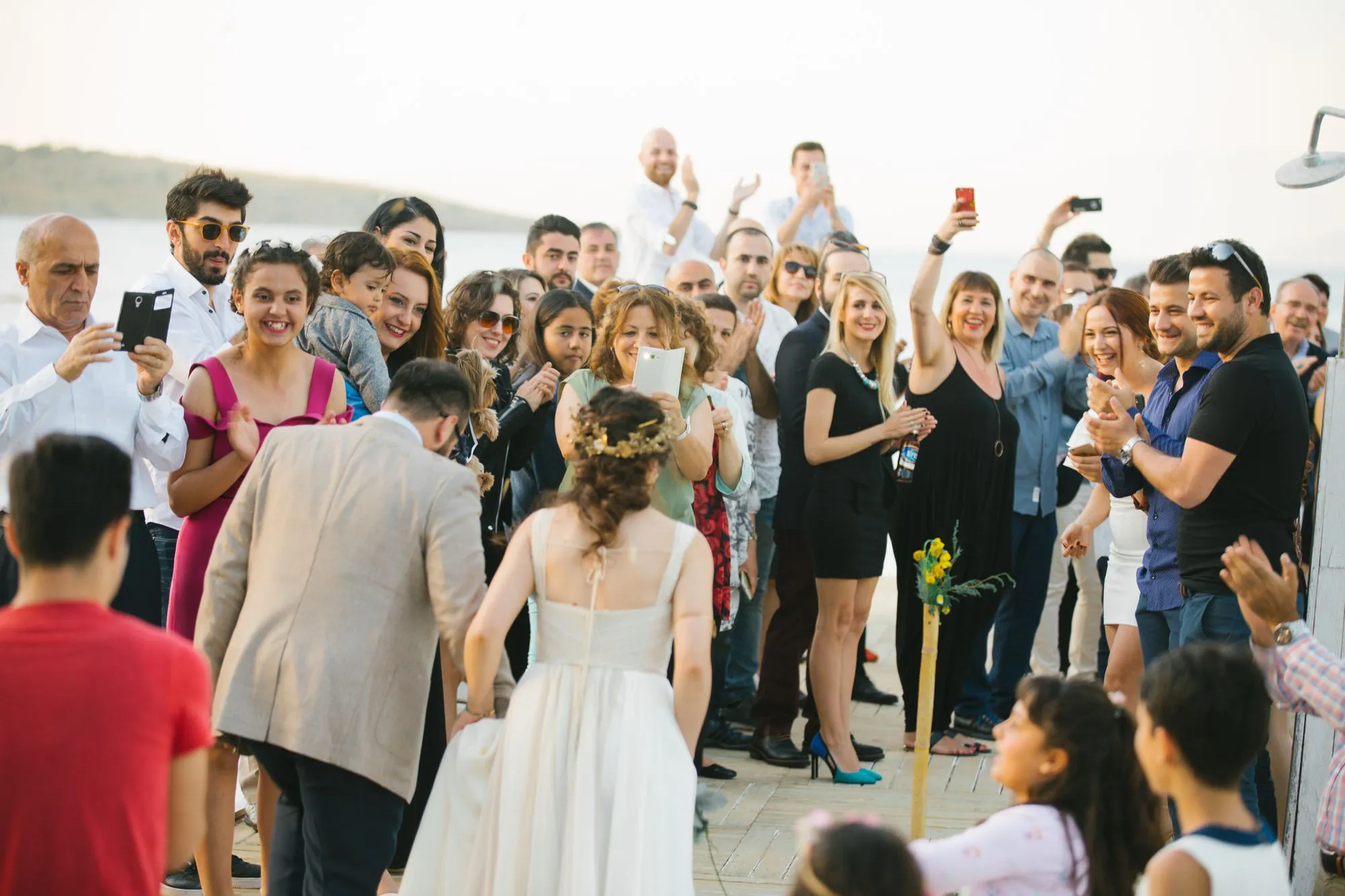 A crowd of wedding guests applauding as the couple walks past at an outdoor reception